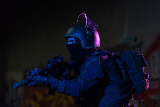 Army soldier in Combat Uniforms with an assault rifle and combat helmet night mission dark background. Blue and purple gel light effect. photo
