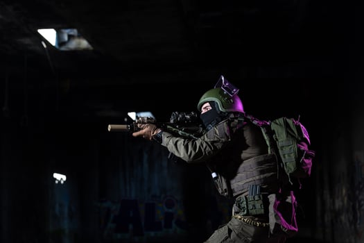 Army soldier in Combat Uniforms with an assault rifle and combat helmet night mission dark background. Blue and purple gel light effect. photo