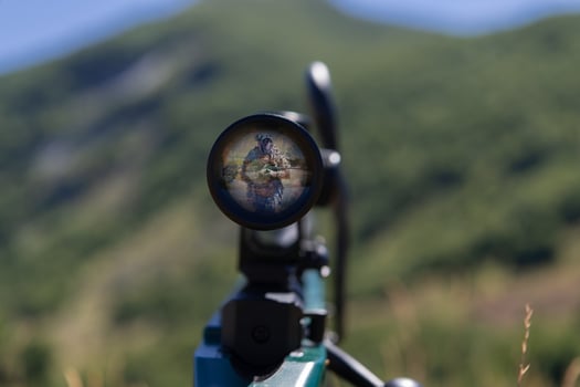 A green military sniper rifle with a scope for long distance tactical modern warfare in yellow grass blue sky photo