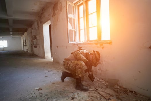 soldier in action near window changing magazine and take cover photo