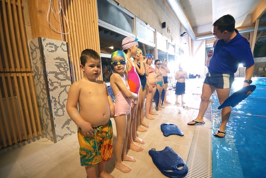 a group of children in swimsuits standing in a pool photo