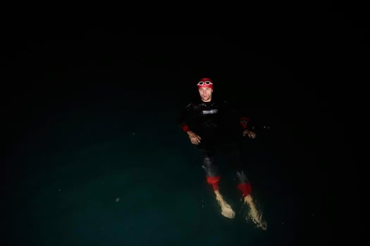 triathlon athlete swimming in dark night  wearing wetsuit photo