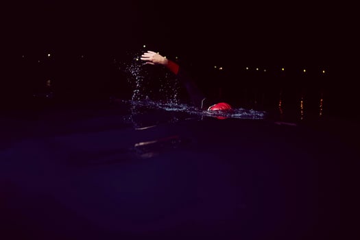 triathlon athlete swimming in dark night  wearing wetsuit photo