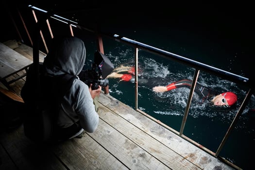 videographer  taking action shot of triathlon swimming athlete at night photo