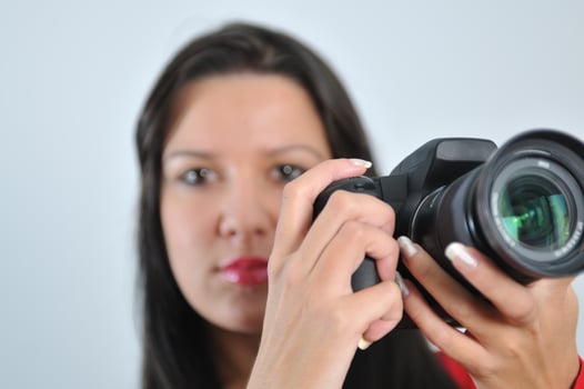 Young woman holding camera in hand taking picture isolated photo