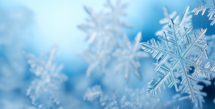Close-up of delicate snowflakes in low relief against a serene icy blue background providing ample space for captivating winter photo