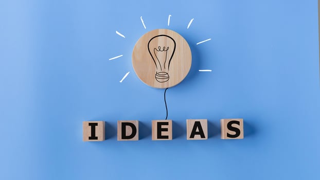 Ideas concept with light bulb and wooden cubes on blue background. Creative thinking ideas and innovation concept. photo