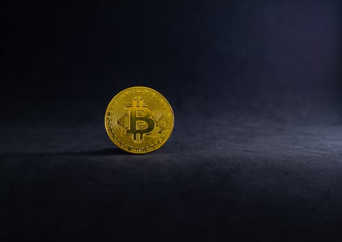 Golden Bitcoin on the floor with black background. Gold digital coin on black with light and shadow. photo
