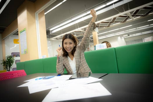 Beautiful asian business woman sitting and celebrating with happiness on her desk. photo