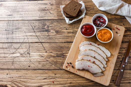 Pieces of smoked boiled pork on a wooden rustic Board with bread, sauces and spices on a wooden table. Copy space photo