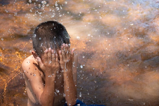 Asian young boy cute and charming playing water in the river on the background of green rice fields and sunrises,child playing water,thai children's lifestyle,happy,fun,joy. photo