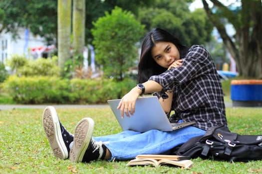 happy asian student reading a book and using laptop to study for advancement, look to camera photo