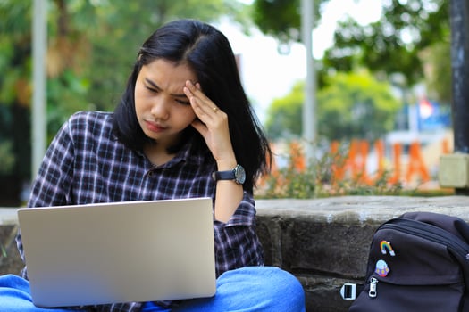 exhausted and stressed asian woman student working using laptop and study with text books in outdoors photo