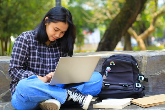young smiling asian woman using laptop and writing notebook, cheerful asian student watching webinar and studying from e course photo