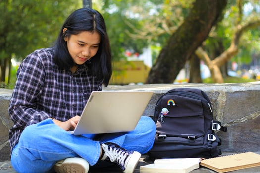 young smiling asian woman using laptop and writing notebook, cheerful asian student watching webinar and studying from e course photo