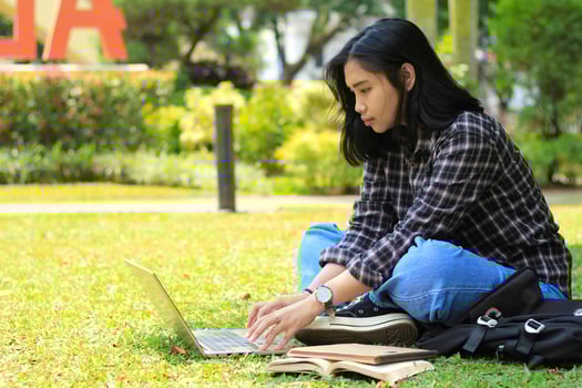 portrait of focused young asian woman surfing internet using laptop to working remotely, read book, and writing in notebook. attractive asian student study in outdoors photo