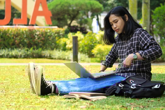 portrait of focused young asian woman surfing internet using laptop to working remotely, read book, and writing in notebook. attractive asian student study in outdoors photo