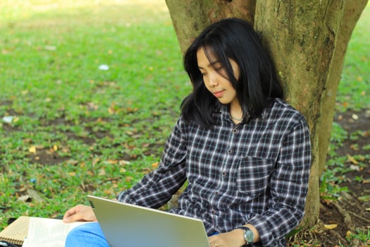 portrait of focused young asian woman surfing internet using laptop to working remotely, read book, and writing in notebook. attractive asian student study in outdoors photo