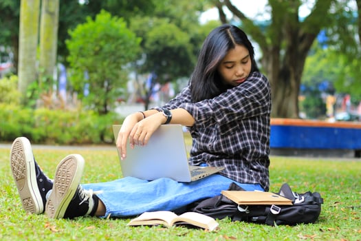 portrait of focused young asian woman surfing internet using laptop to working remotely, read book, and writing in notebook. attractive asian student study in outdoors photo