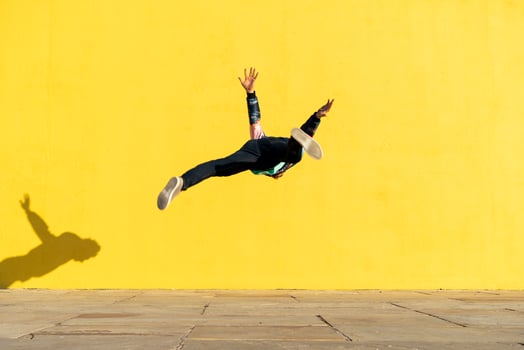 Acrobat jumping somersaults in front of yellow wall photo