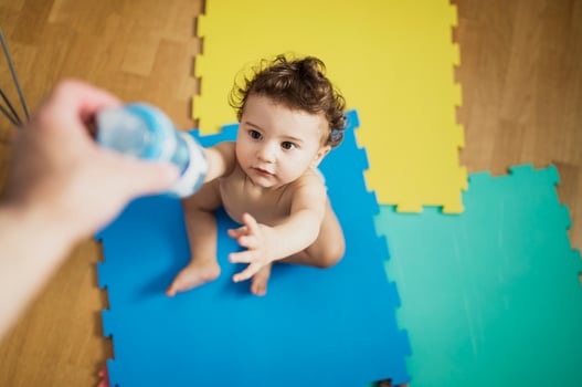 Father's hand giving baby boy a bottle of water photo