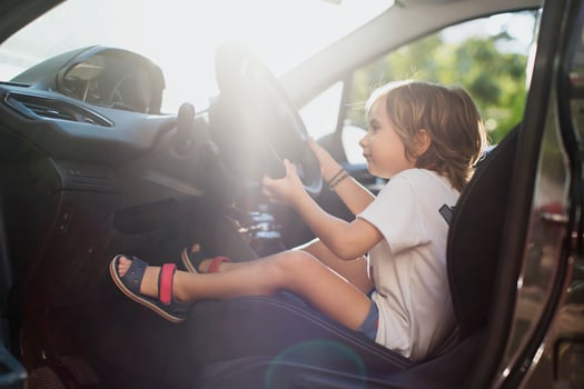 Happy little boy sitting on driver's seat in a car photo