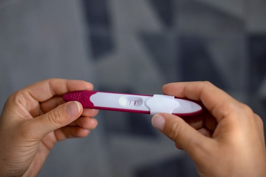 Close-up of woman's hands holding positive pregnancy test photo