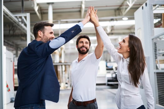 Happy businessman and employees high fiving in a factory photo