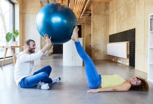 Happy man and woman practicing with fitness ball in modern office photo