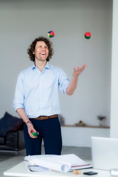 Laughing businessman juggling balls in his office photo