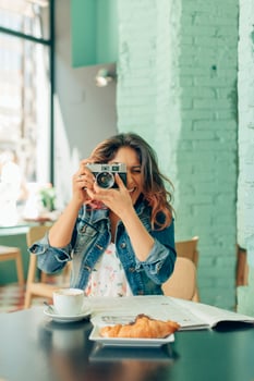 Laughing woman sitting at coffee shop taking pictures with camera photo