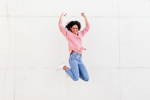 Happy young woman jumping in the air against light background photo