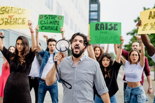 Man shouting through megaphone while protesting with people on street photo