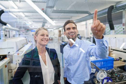 Happy young male technician pointing at graphical interface on glass in factory photo