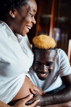 Happy man with pregnant young woman on couch photo