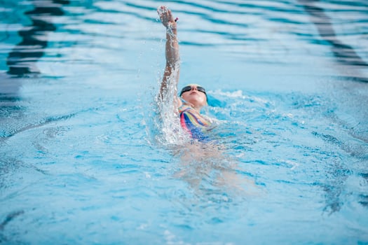 Young woman swimming in swimming pool, backstroke photo