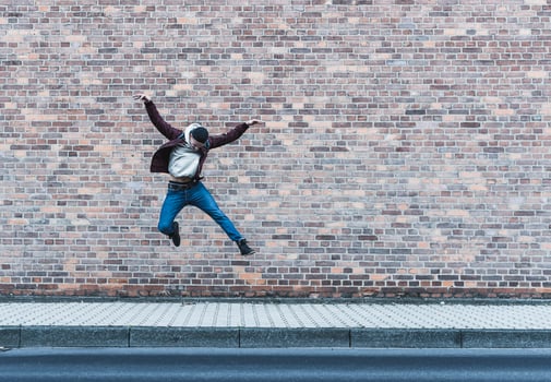 Young man jumping in front of brick wall photo