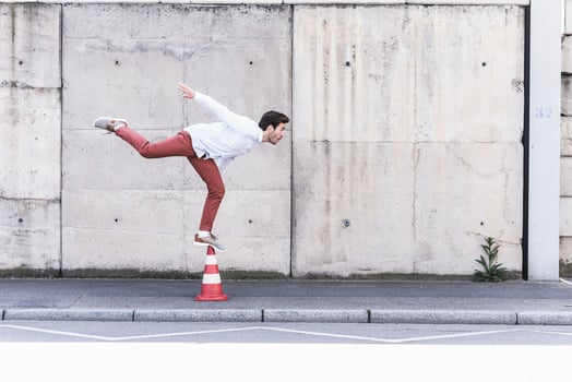Young man balancing on traffic cone in front of concrete wall photo