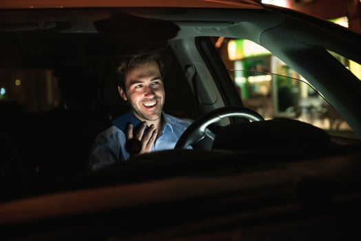 Happy young man using cell phone in car at night photo
