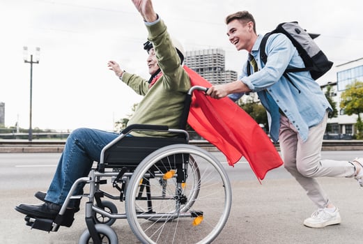 Young man pushing senior man sitting in a wheelchair dressed up as superhero photo