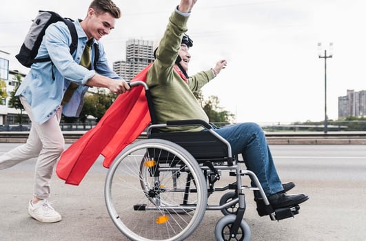 Young man pushing senior man sitting in a wheelchair dressed up as superhero photo