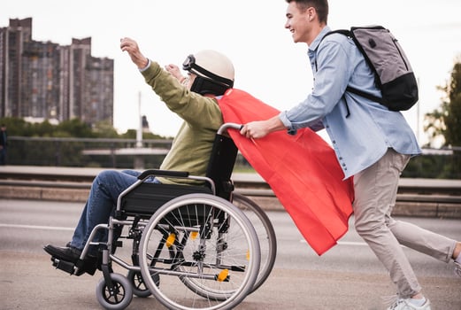 Young man pushing senior man sitting in a wheelchair dressed up as superhero photo