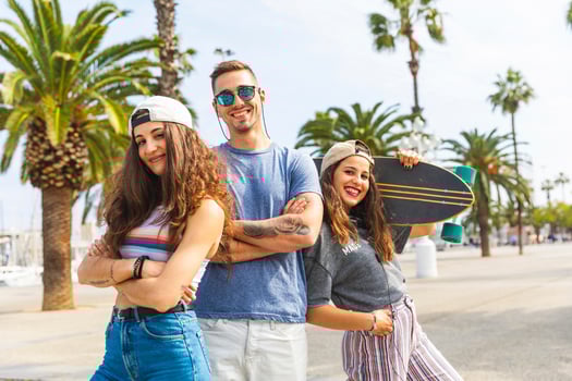 Three happy friends posing with skateboard on a promenade with palms photo