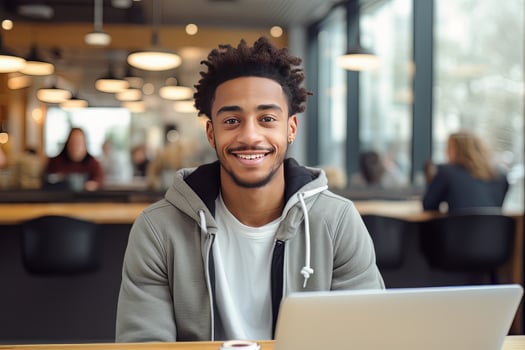 Portrait of Cheerful Black Male Student Learning Online in Coffee Shop, Young African American Man Studies with Laptop in Cafe, Doing Homework photo