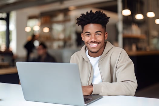 Portrait of Cheerful Black Male Student Learning Online in Coffee Shop, Young African American Man Studies with Laptop in Cafe, Doing Homework photo