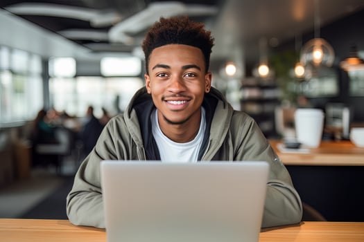 Portrait of Cheerful Black Male Student Learning Online in Coffee Shop, Young African American Man Studies with Laptop in Cafe, Doing Homework photo