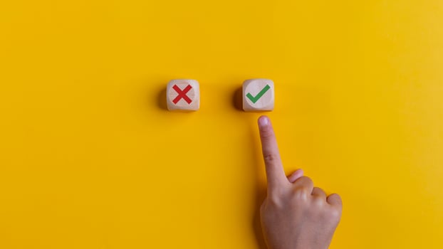 Right and wrong icons on wooden cubes with hand choosing the right icon on yellow background. Approving, voting, or right decision concept. photo