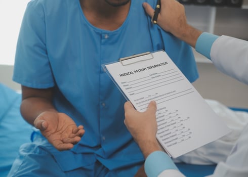 Close up of doctor sitting on bedside of male patient in hospital photo