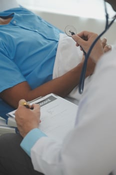 Close up of doctor sitting on bedside of male patient in hospital photo