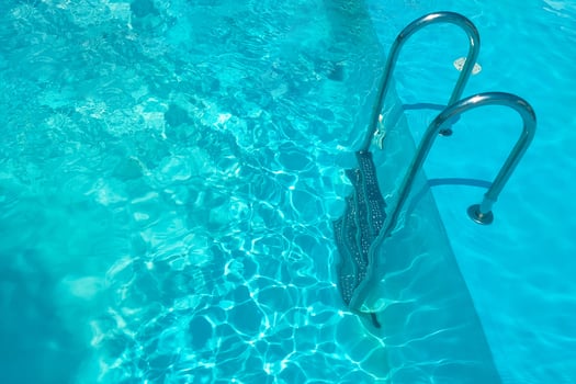 Staircase in the swimming pool with blue water in the background photo